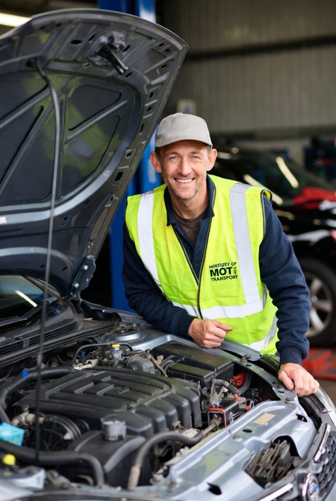 Solicitor reviewing MOT VT01 paperwork with garage owner in a vehicle testing bay